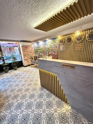 A reception area with a check-in counter, a reception desk, and a patterned floor.