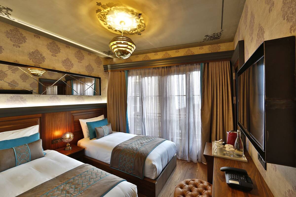 A hotel room with two beds, a large mirror, a TV, and a telephone.