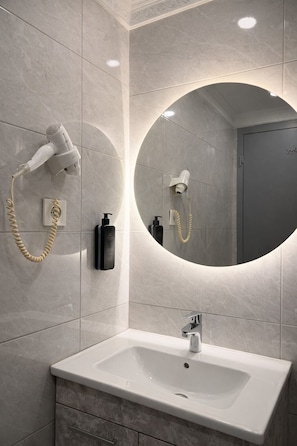A bathroom with a large mirror, two hair dryers, a sink, and a towel rack. - Peak Star Hotel  (Istanbul)