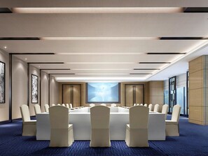 Un salón de conferencias con una mesa larga, sillas y una pantalla grande.