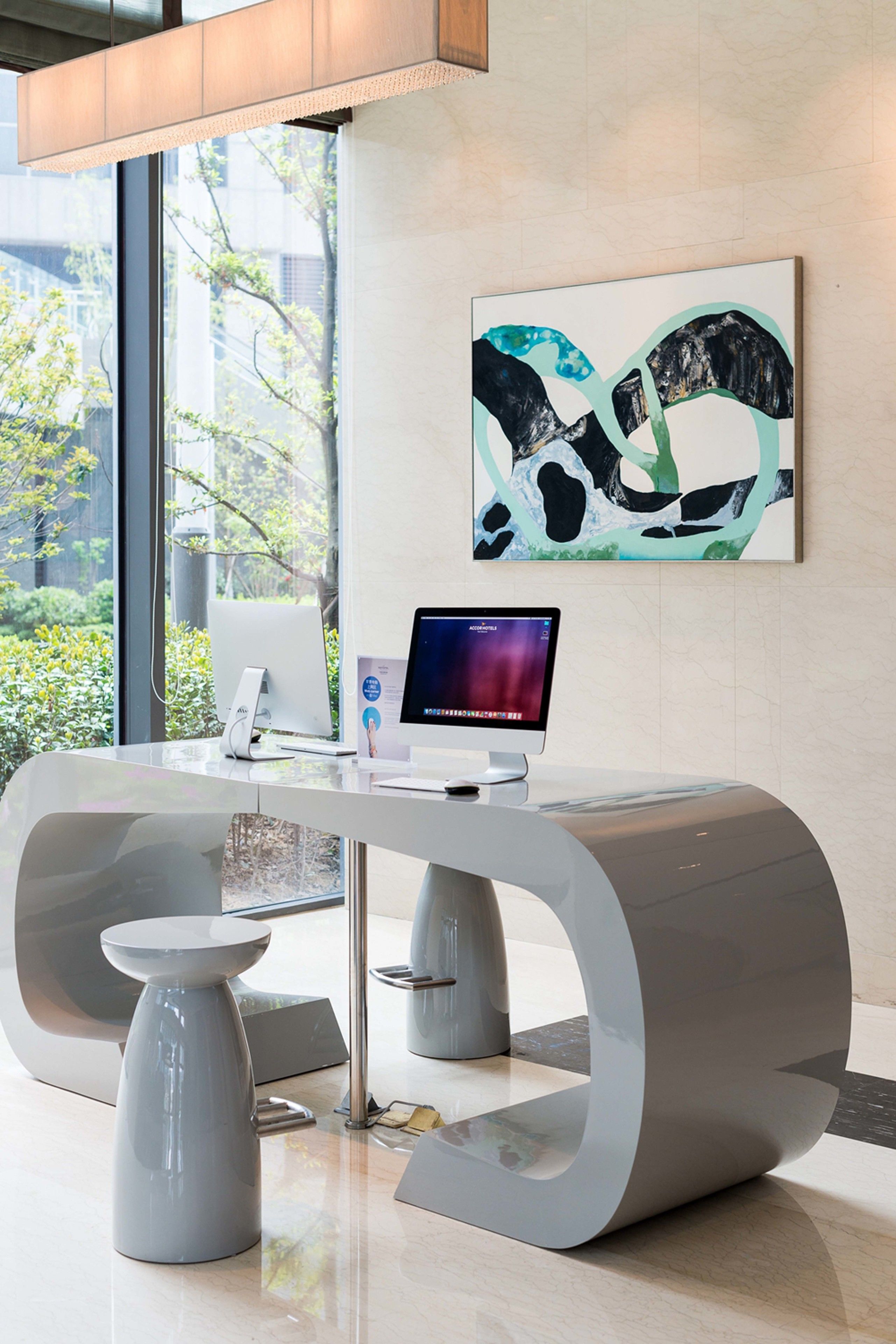 Ein moderner Empfangstresen mit einem Computermonitor und einem gerahmten abstrakten Kunstwerk an der Wand.