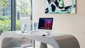 Un mostrador de recepción de diseño moderno, con un monitor de computadora y una obra de arte abstracta enmarcada en la pared.