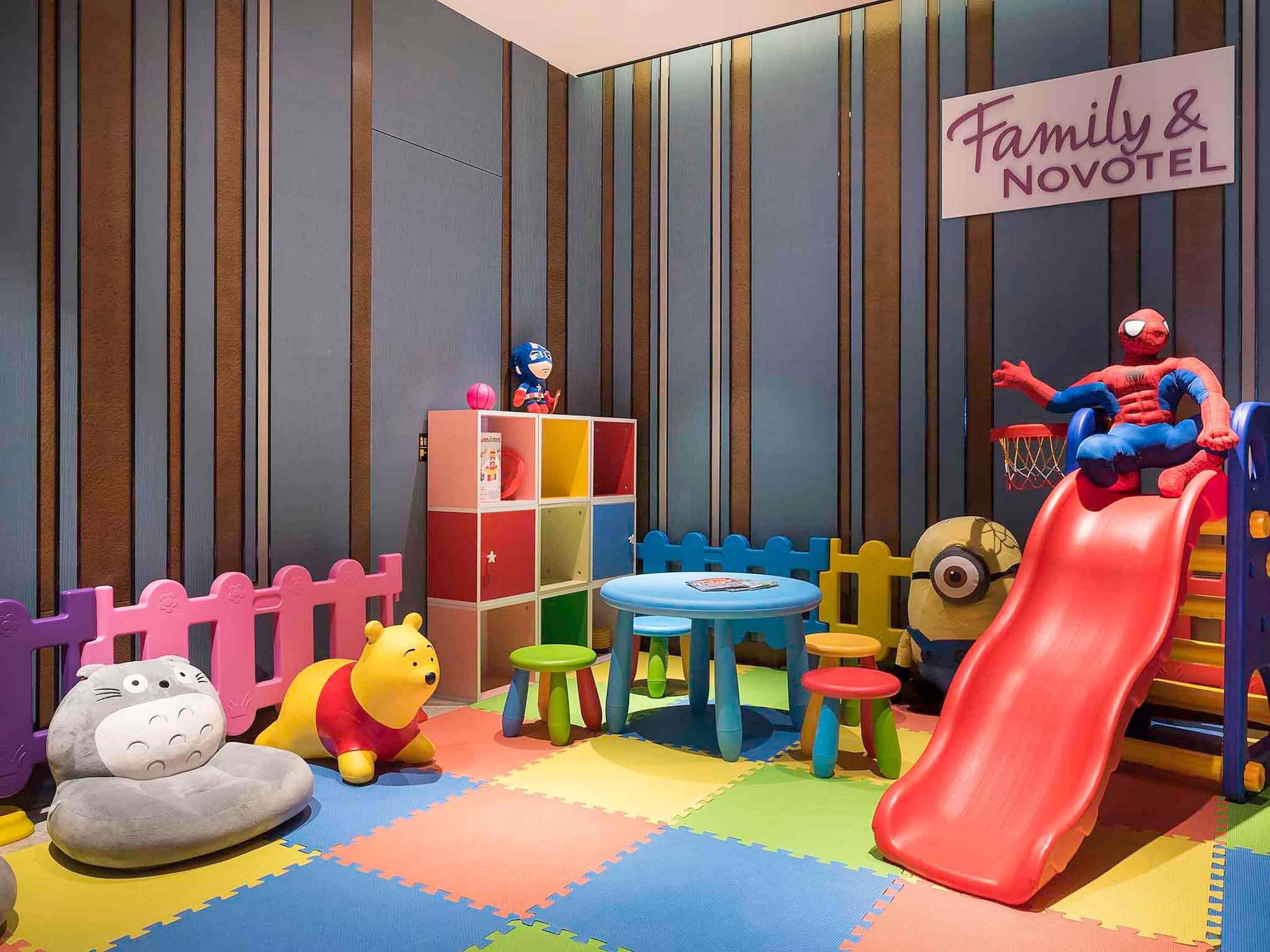 A children's play area with a slide, toys, and a sign reading 'Family & Novotel'.