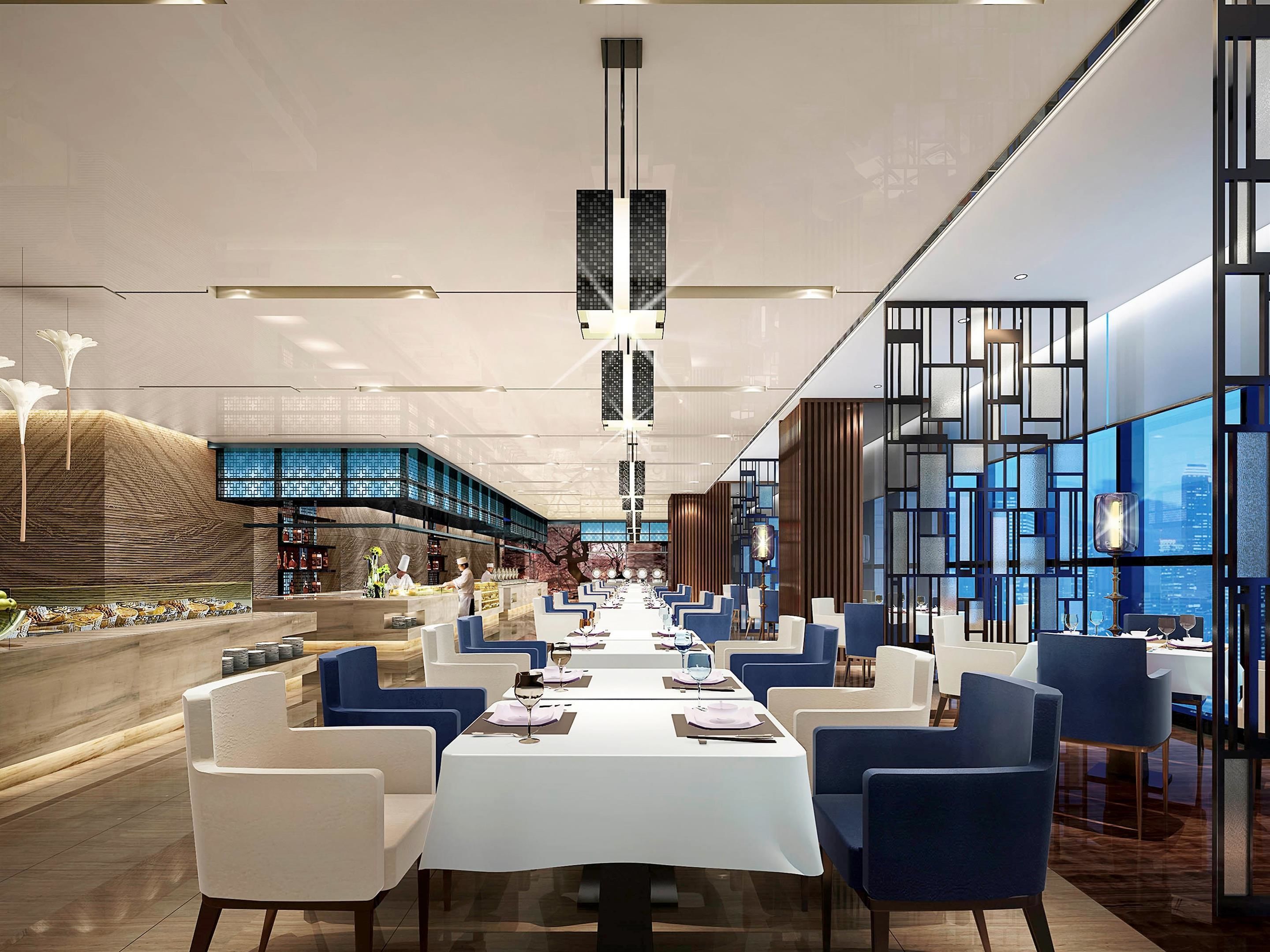 A modern dining area with long tables, blue and white chairs, and a central walkway.