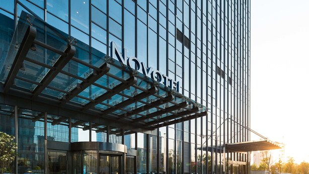 A modern hotel with a glass facade, a covered entrance, and a clear view of the surrounding area. - Novotel Ningbo East (Ningbo)