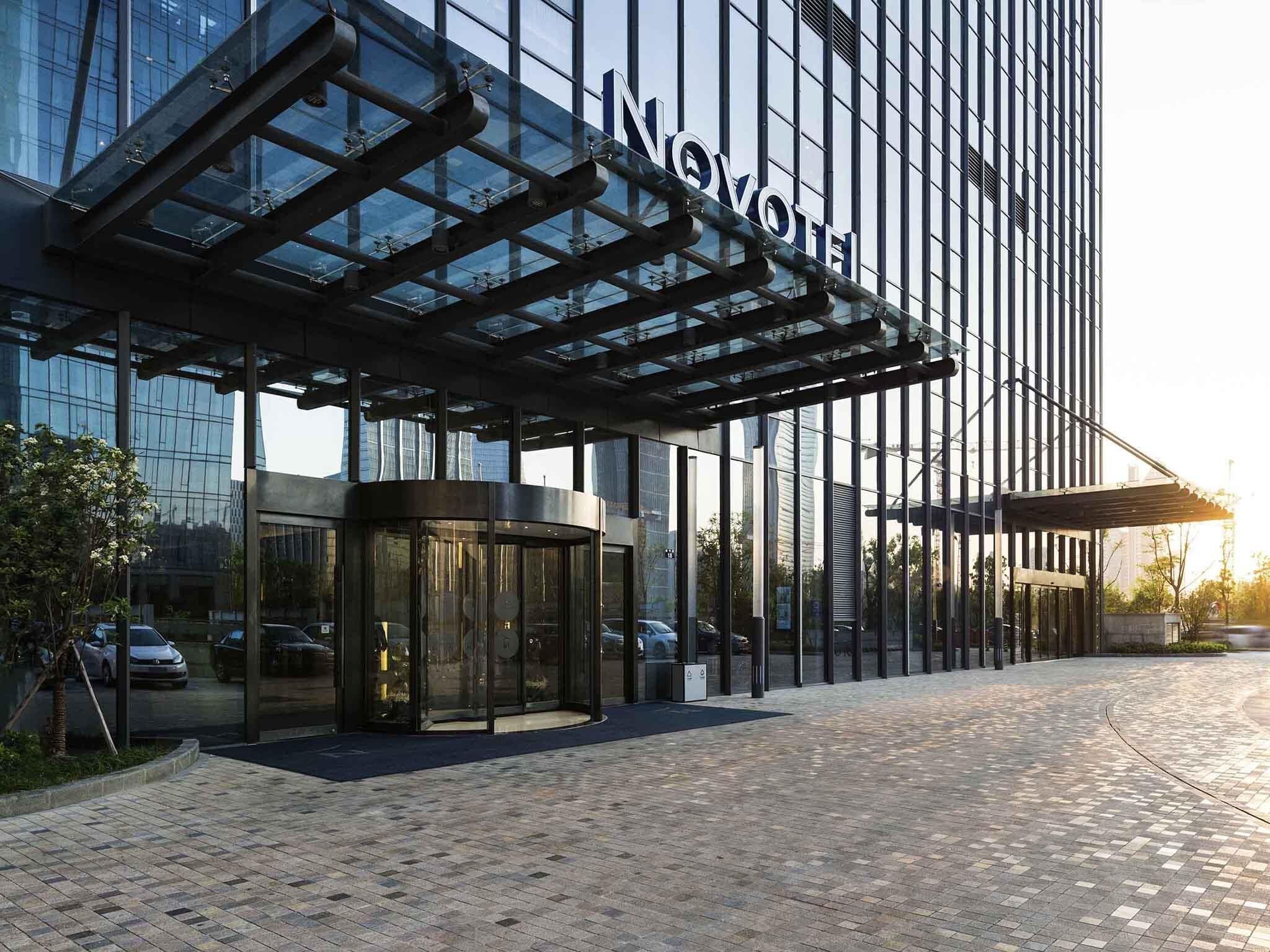 A modern hotel with a glass facade and a covered entrance.