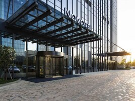 A modern hotel with a glass facade and a covered entrance.