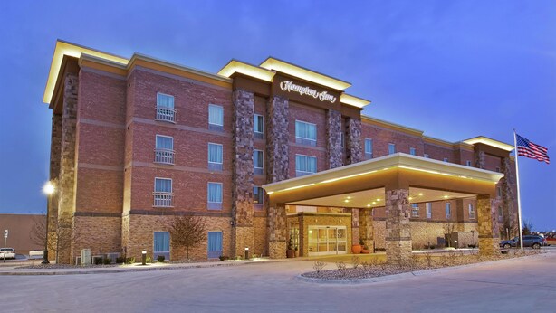 A hotel with a brick facade, a covered entrance, and an American flag.
