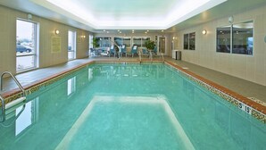 A swimming pool with clear water, a tiled deck, and a sunlit interior.