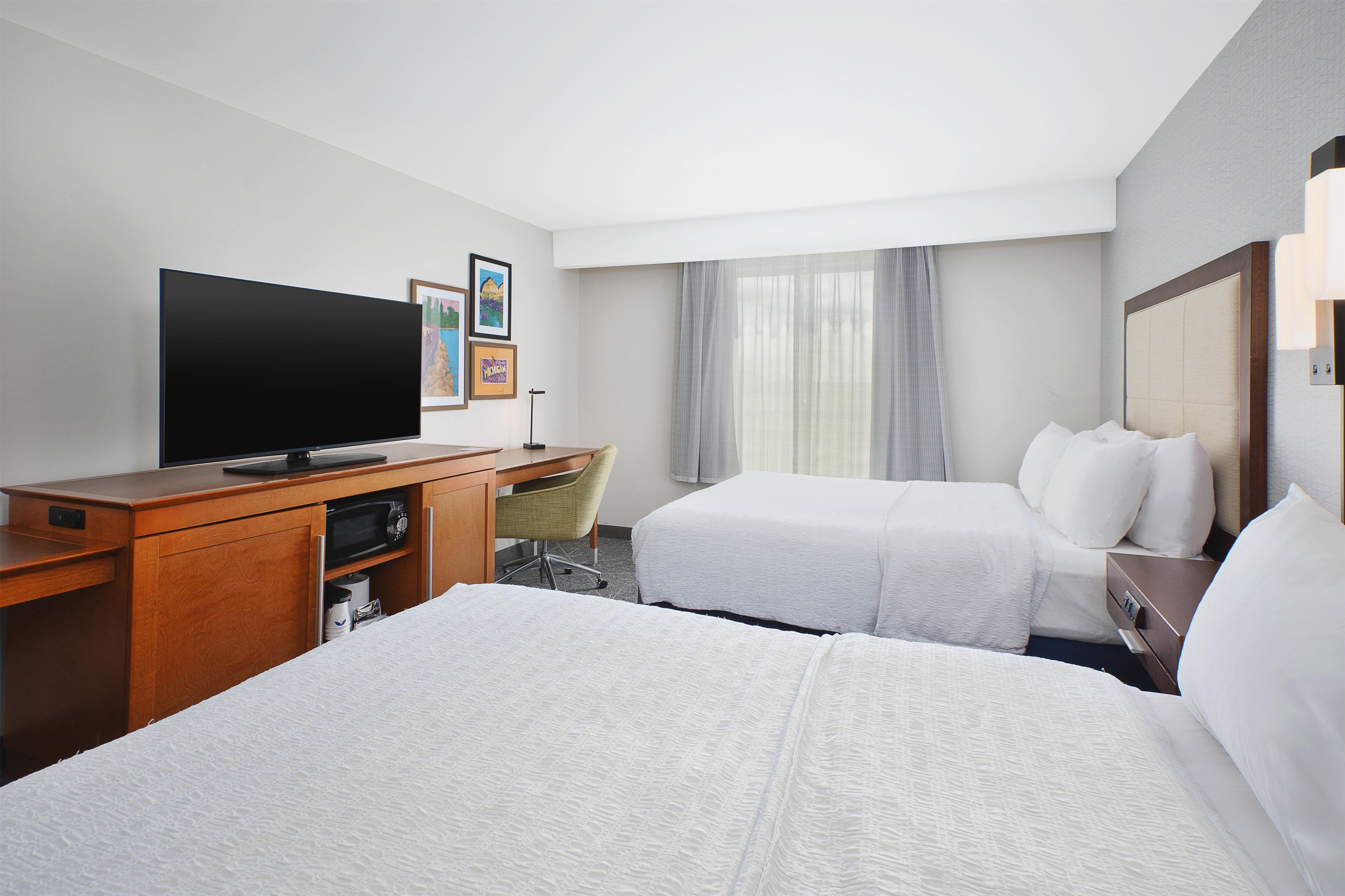 A hotel room with a bed, a desk, a television, and a chair.