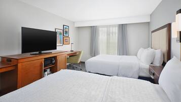 A hotel room with a bed, a desk, a television, and a chair.