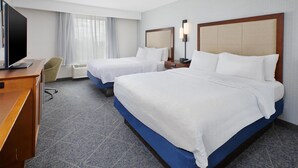 A hotel room with two beds, a desk with a computer, a chair, and a television.