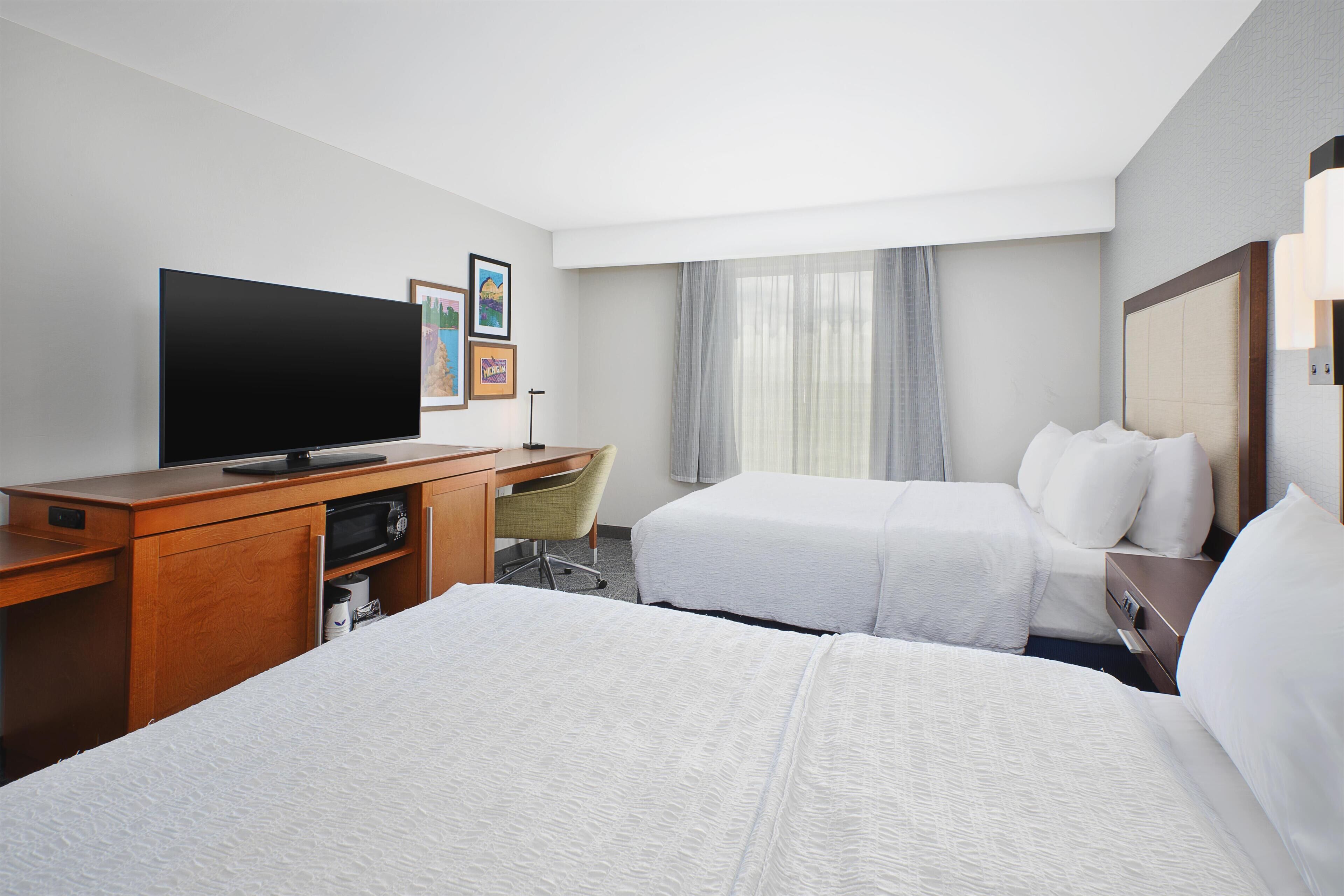 A hotel room with a bed, a desk, a television, and a chair.