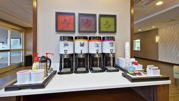 Un espace dédié au café, équipé de quatre distributeurs, de distributeurs d’assaisonnements et d’un plateau contenant des tasses et des condiments.