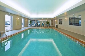 Une piscine intérieure à l’eau claire, équipée d’un dispositif d’élévation pour faciliter l’accès et de chaises longues.