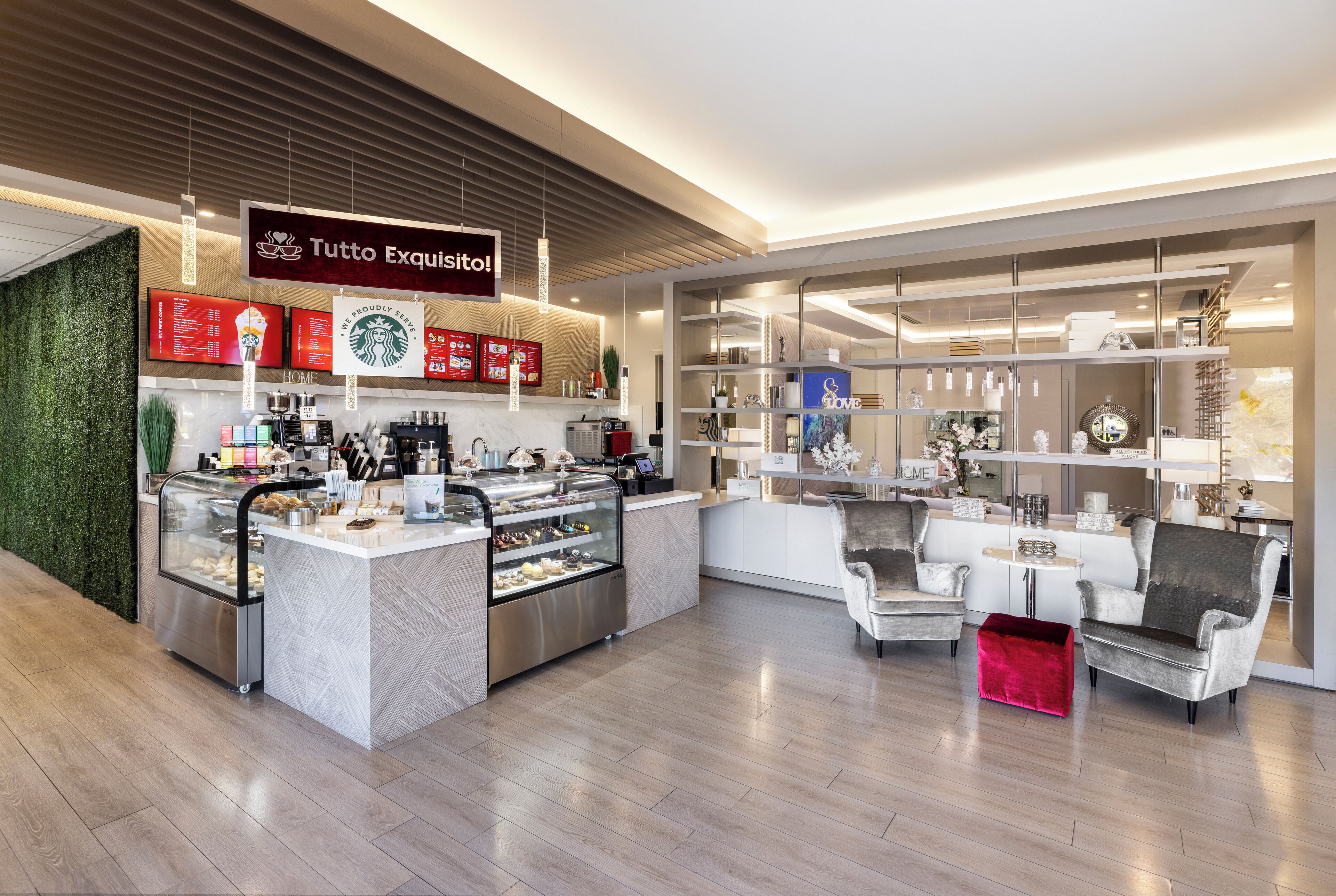 Een moderne koffiebar met een glazen vitrine, een zithoek en een bord met de tekst 'Tutto Esquisito!'.