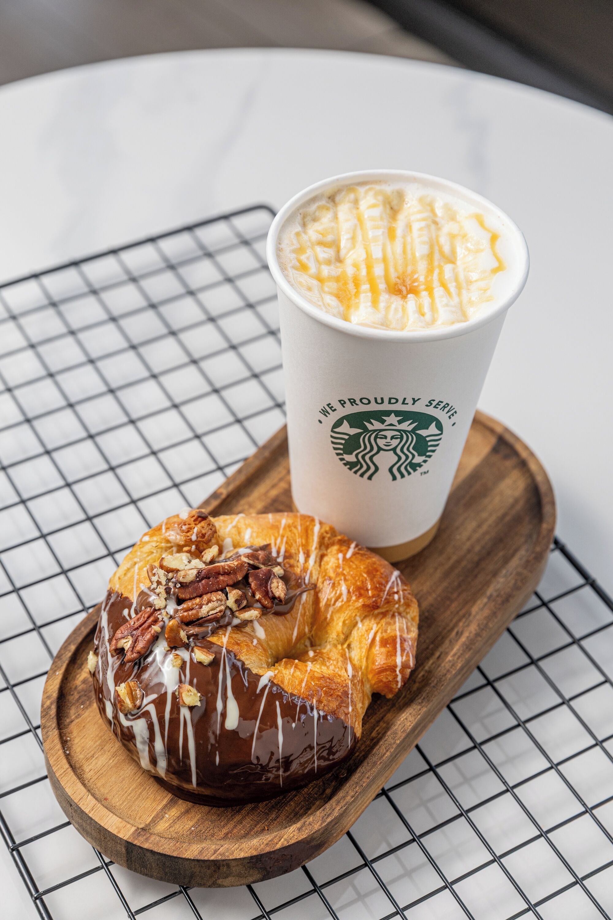 Une pâtisserie sur une planche en bois, à côté d’un gobelet Starbucks.