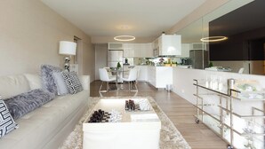 Un soggiorno moderno con un divano, un tavolino e una zona cucina sullo sfondo.