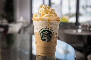A Starbucks cup with whipped cream and caramel drizzle.