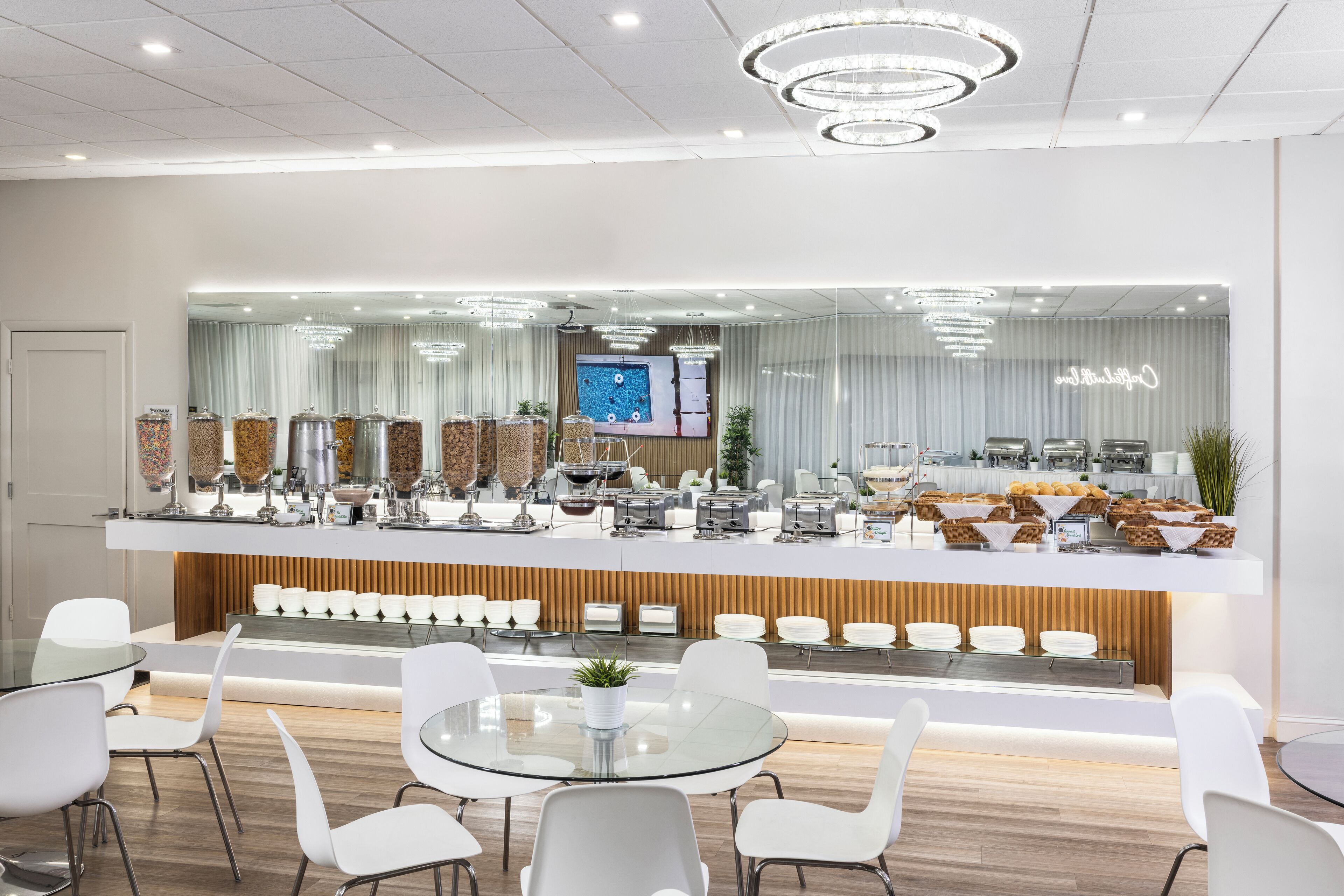 A modern hotel lobby with a reception desk, seating area, and a large screen displaying a sports game.