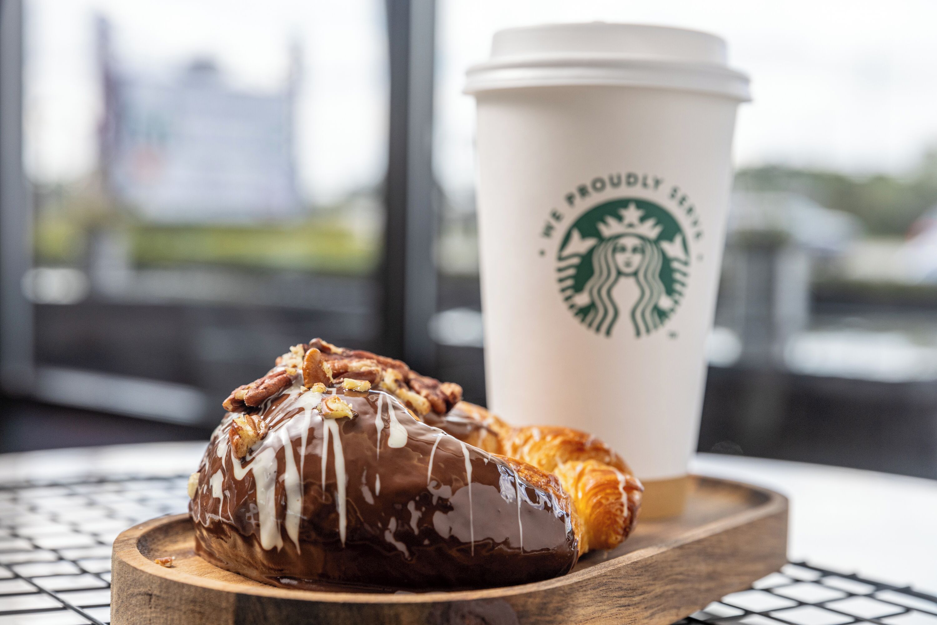 Ein Gebäck auf einer Holzbrett neben einem Starbucks-Becher.