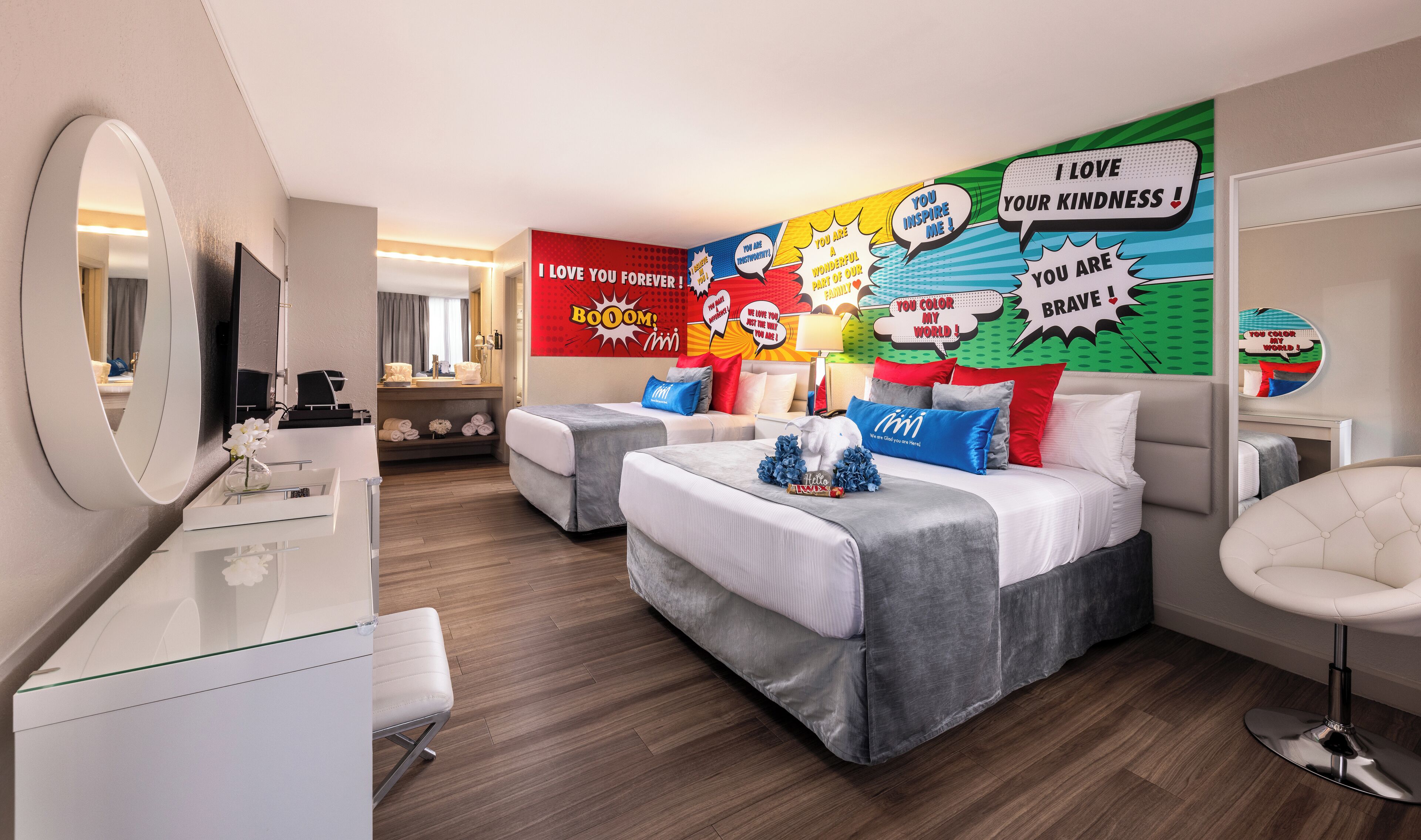 Ein modernes Hotelzimmer mit zwei Betten, einem Schreibtisch und einem Spiegel.