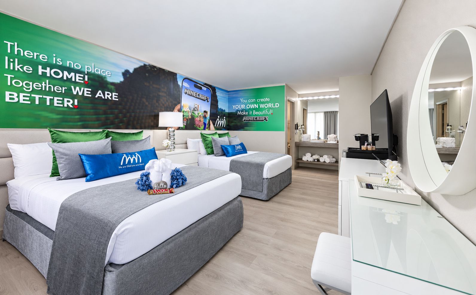 A hotel room with two beds, a TV, a mirror, and a wall with motivational posters.