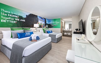 Habitación de hotel con dos camas, un televisor, un espejo y una pared decorada con carteles de motivación.