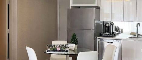 A modern kitchen with white cabinets, a stainless steel refrigerator, and a coffee maker on the counter.