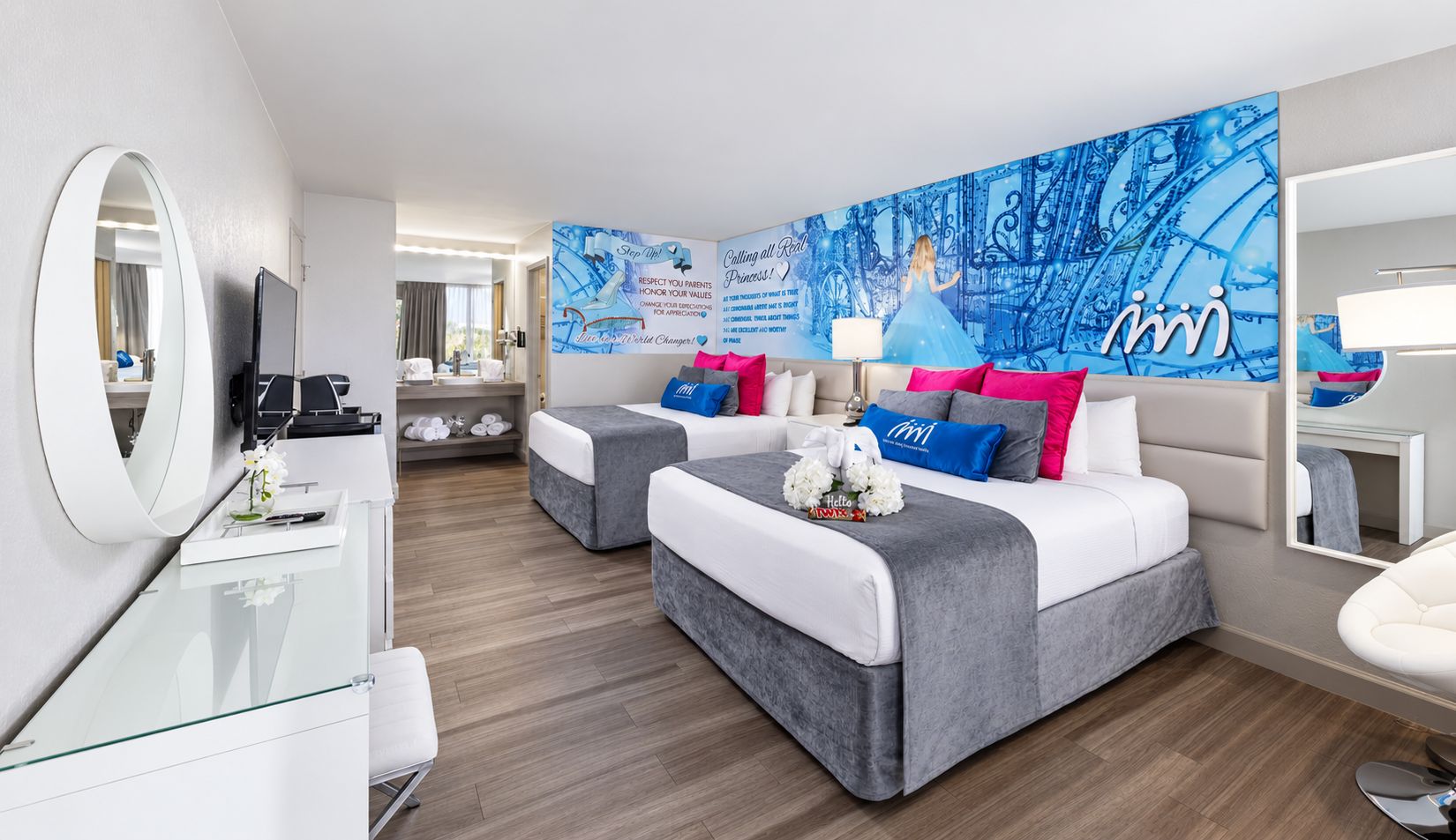A hotel room with two beds, a desk, a mirror, and a wall with a blue abstract design.