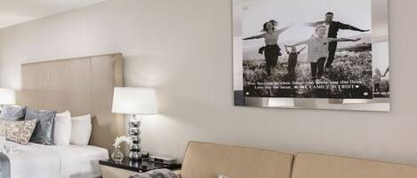 A modern hotel room with a bed, a sofa, a coffee table, and a wall-mounted picture.