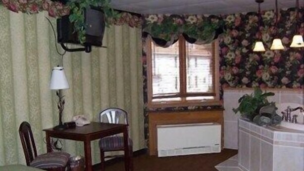 Ein Zimmer mit einem Bett, einem Schreibtisch mit Stuhl, einem Heizkörper und einem Fenster mit Vorhängen.