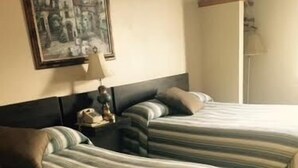 Ein Hotelzimmer mit zwei Betten, einem Nachttisch, einer Lampe und einem gerahmten Bild an der Wand.