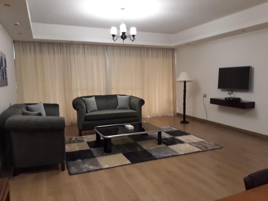 A living room with two sofas, a coffee table, a TV, and a chandelier.