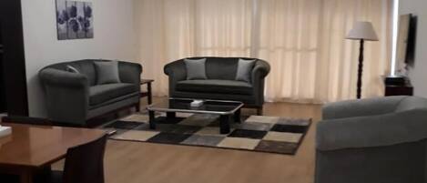 Ein Wohnzimmer mit einer Couch, einem Couchtisch und einem Esstisch mit Stühlen.