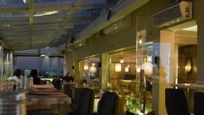 Un restaurante con techo de vidrio, mesas, sillas e iluminación ambiental.