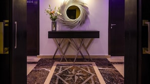 Un vestíbulo moderno con piso de mármol, una mesa consola central y una decoración circular única en la pared.