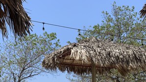 A beachside seating area with wooden lounge chairs and a thatched umbrella, overlooking the ocean. - Banana Beach Hotel (Cóbano)