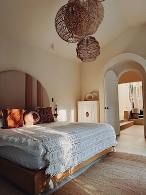 Une chambre avec un grand lit, une armoire et un panier suspendu.