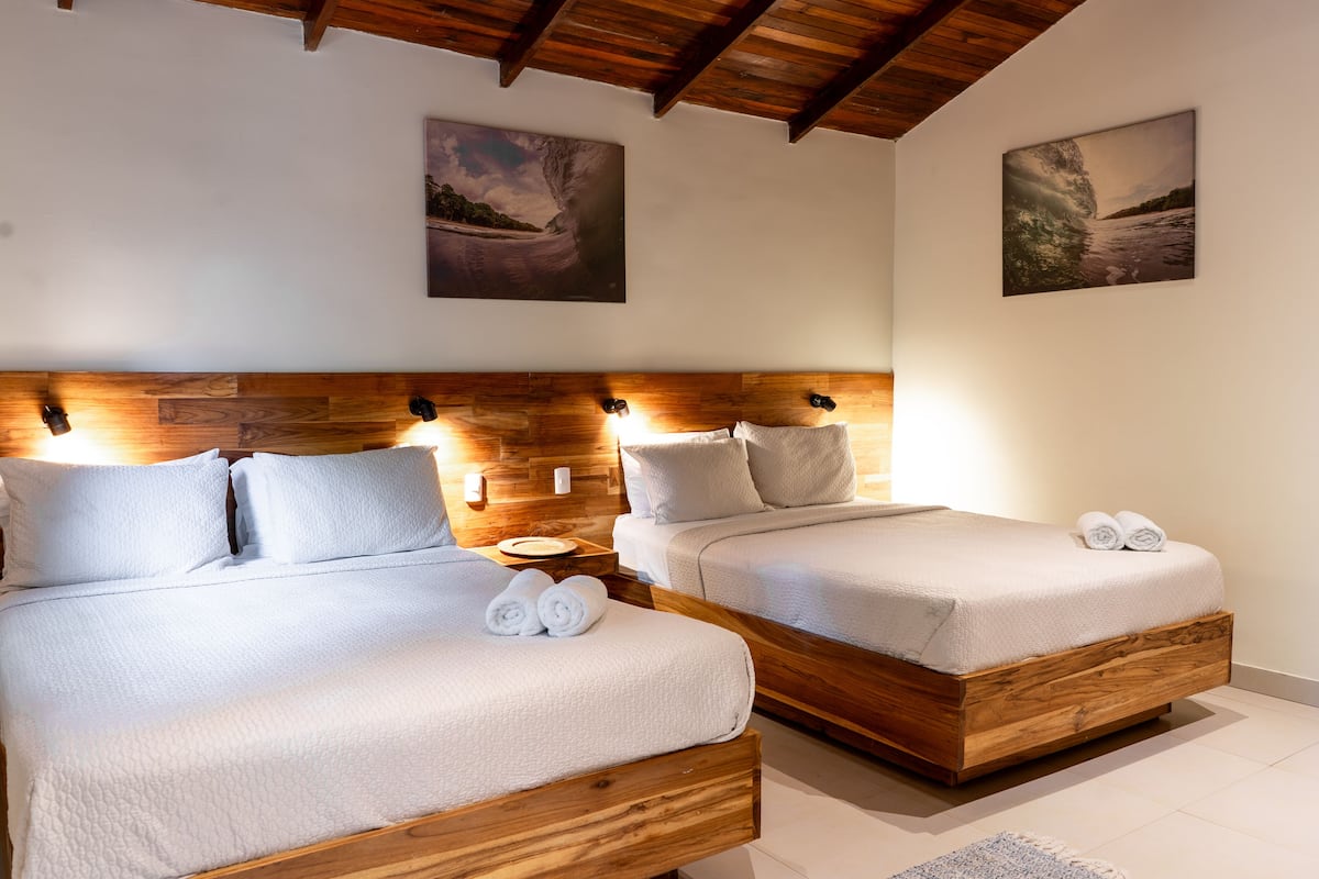 Une chambre avec deux lits, des têtes de lit en bois et des œuvres d’art accrochées aux murs.