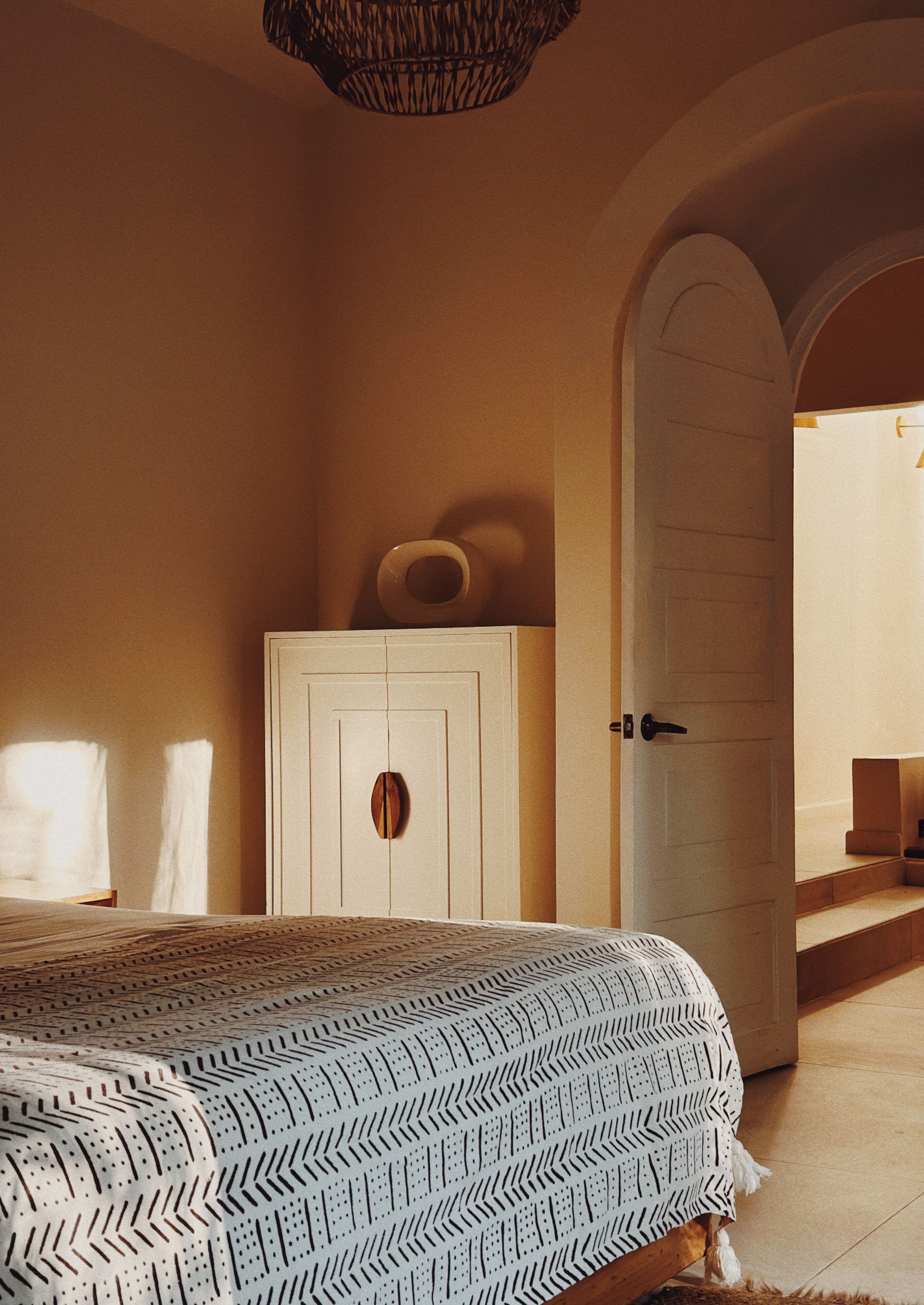 A bedroom with a bed, a wardrobe, and an arched doorway.
