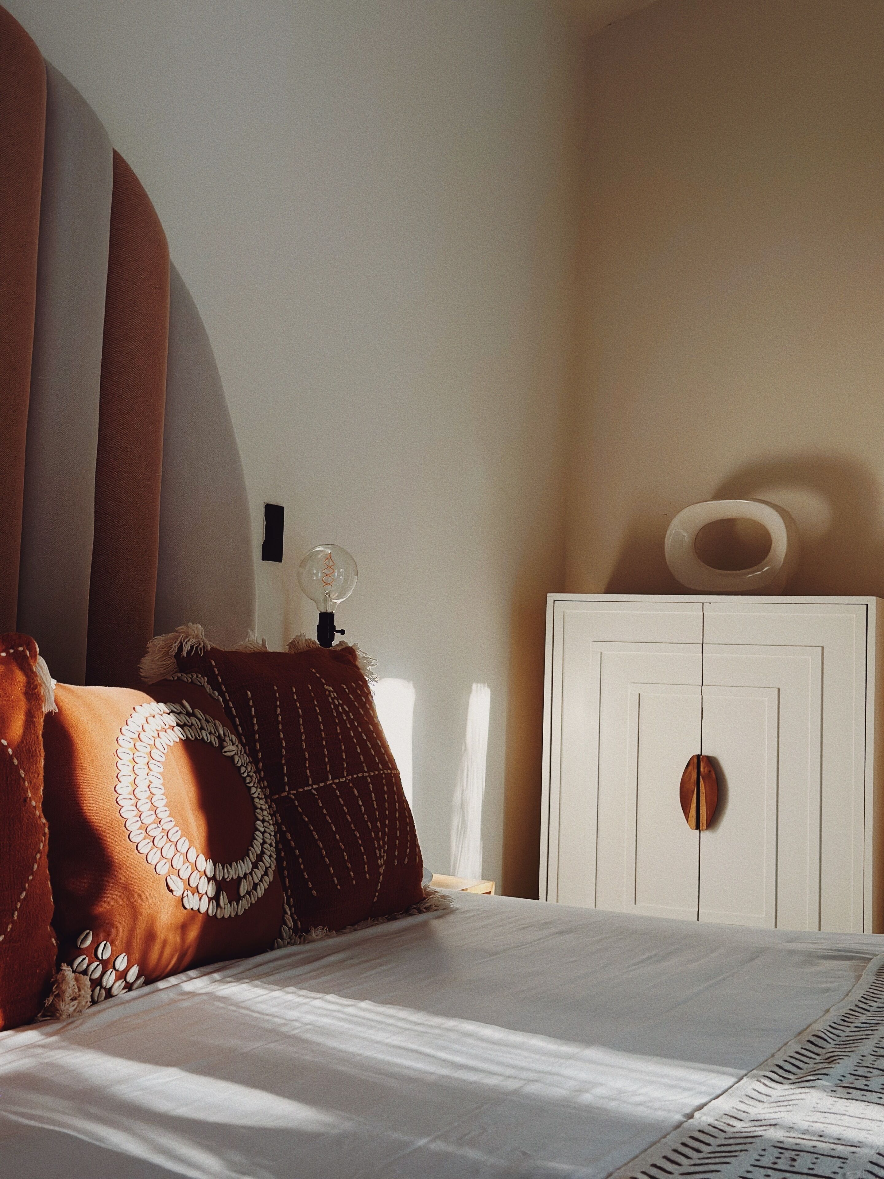 Un dormitorio con cama, almohadas, mesita de noche y armario.