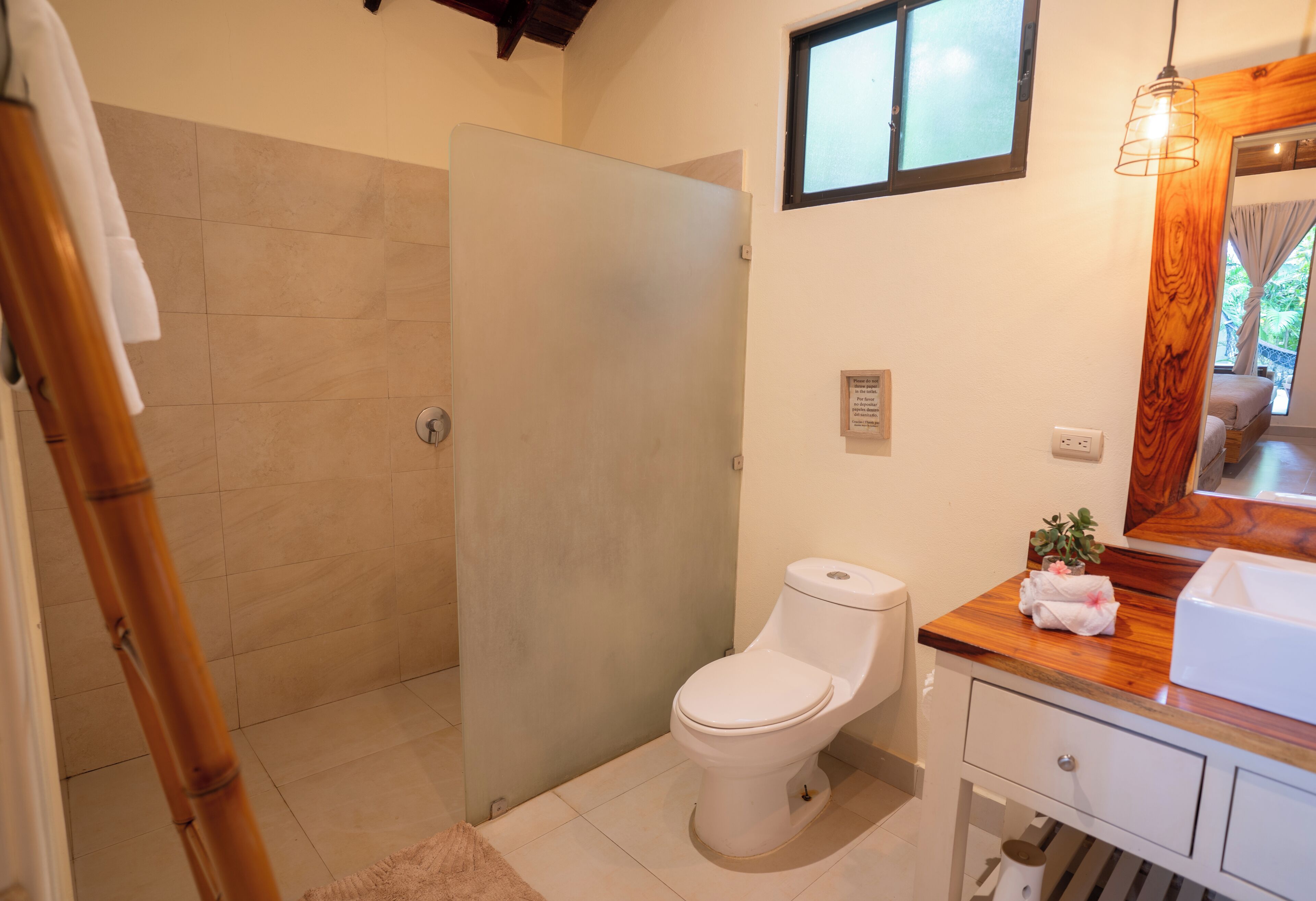 Une salle de bain comprenant des toilettes, un espace douche et un meuble-lavabo avec un miroir.