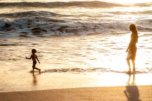 Escena de playa con olas y un niño jugando en el agua.