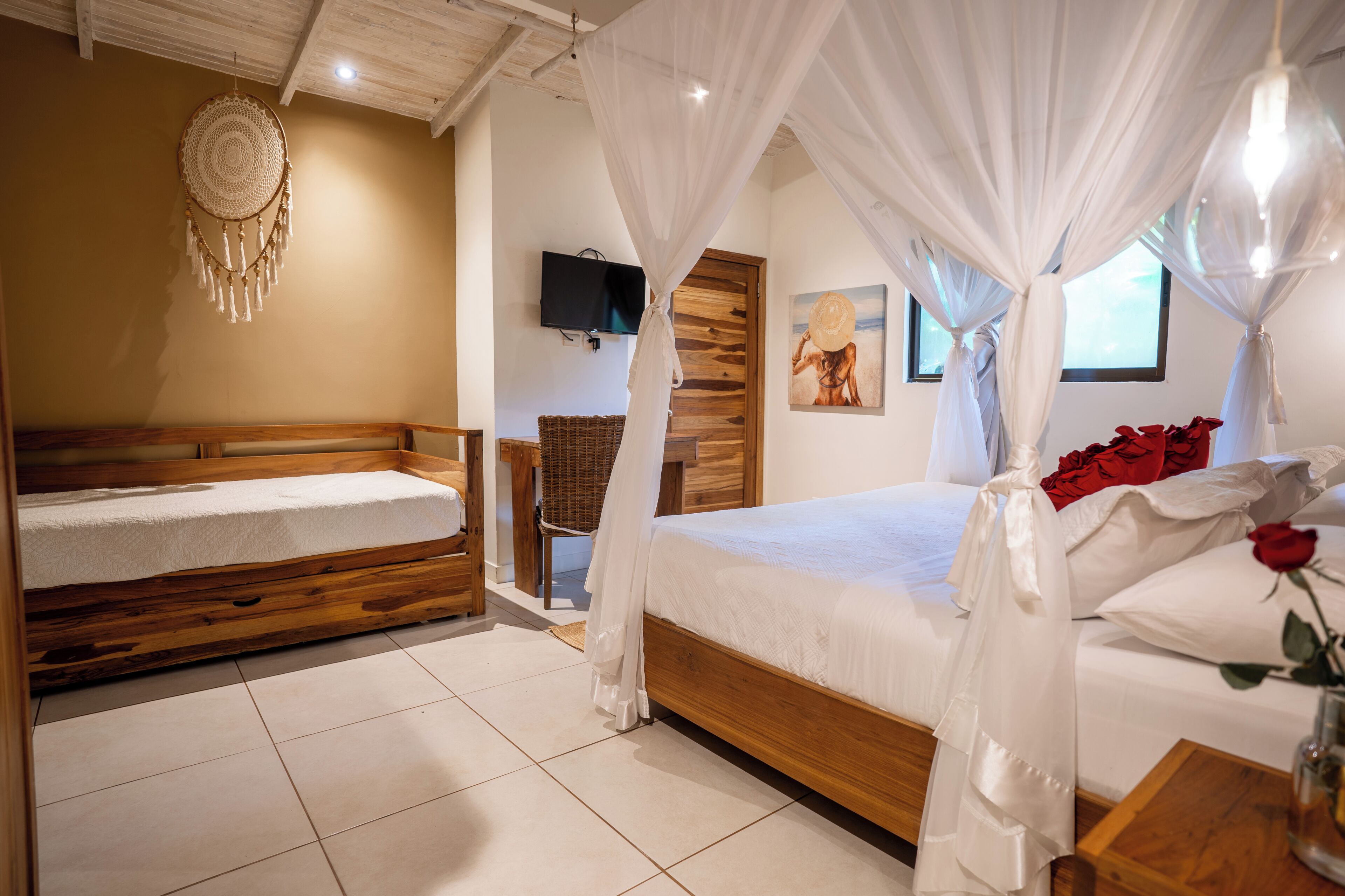 A bedroom with two wooden beds, a television, a wall-mounted artwork, and a decorative wall hanging.