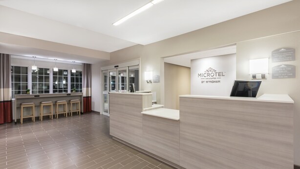 Un área de recepción con mostrador, mostradores de registro y una sala de espera con taburetes.