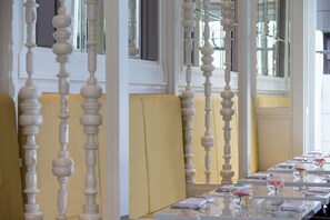 Una larga mesa de comedor con mantel blanco, dispuesta con platos, vasos y cubiertos.