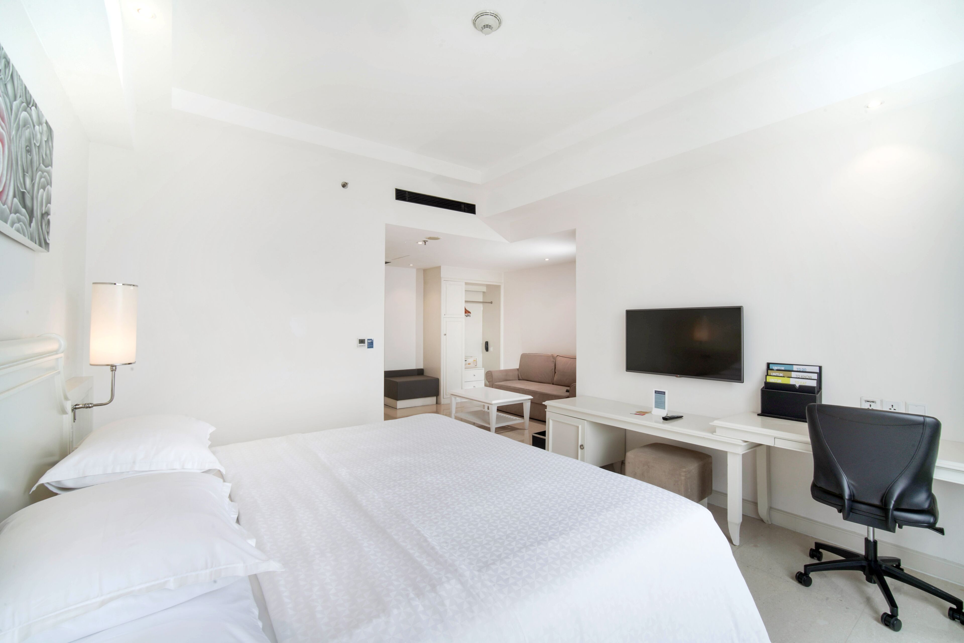 Een hotelkamer met een bed, een bureau, een stoel, een televisie en een lamp.