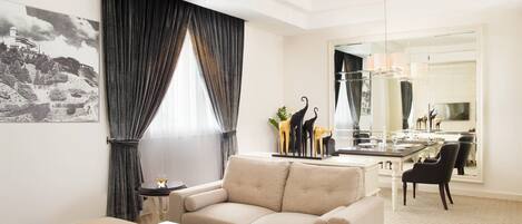 A modern living room with a beige sofa, a white coffee table, and a dining area with a glass table and chairs.