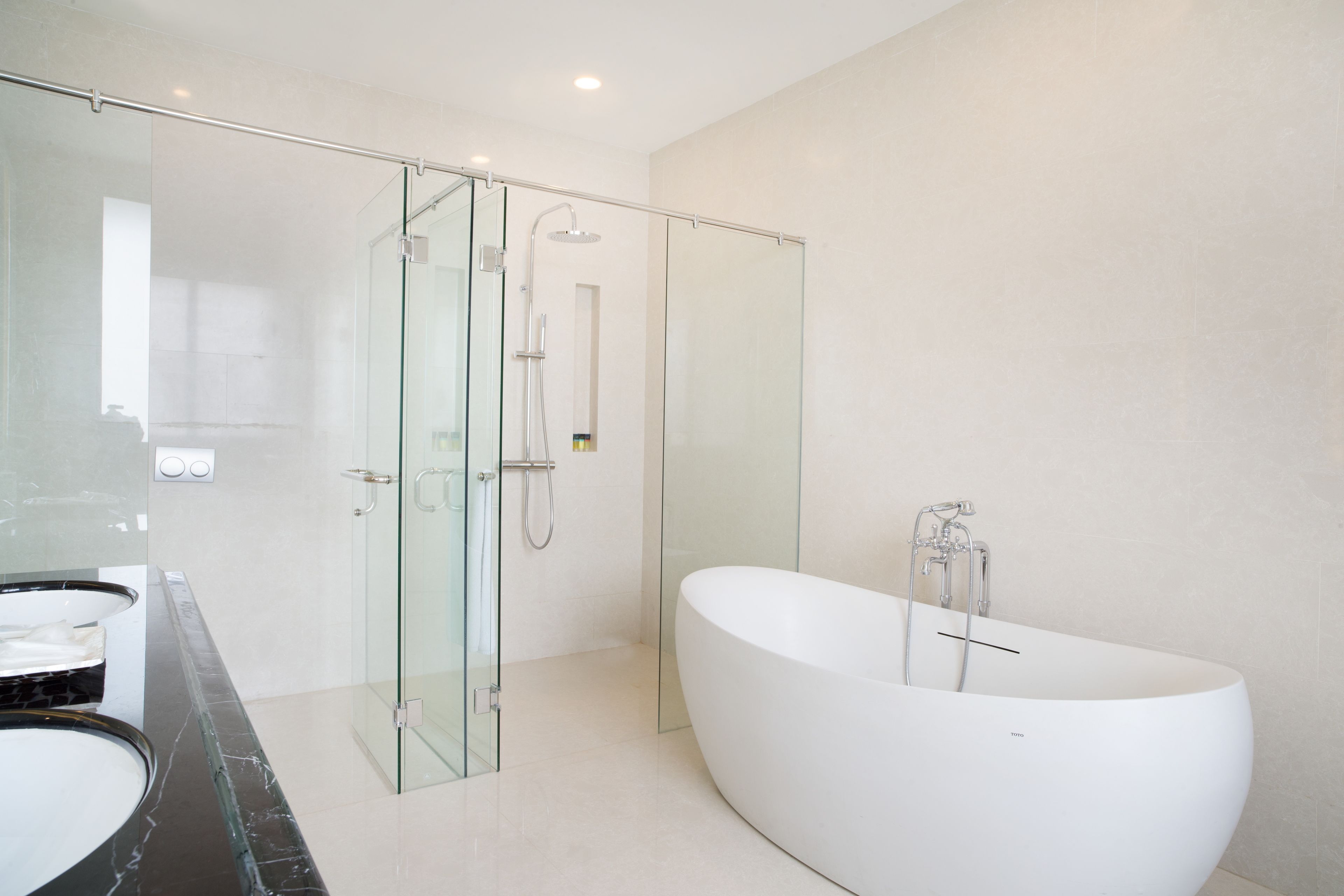 Ein modernes Badezimmer mit einer gläsernen Duschkabine, einer freistehenden Badewanne und einer Marmorplatte mit Waschbecken.